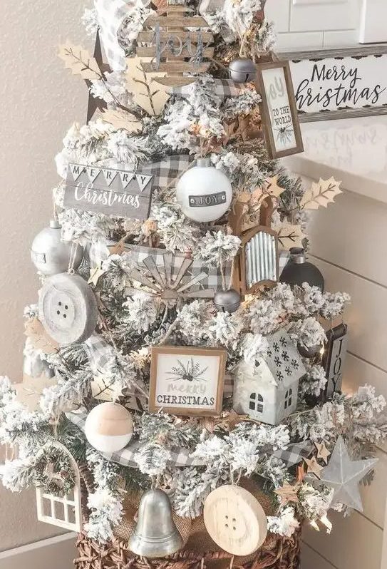 a flocked Christmas tree with wooden ornaments, buffalo check ribbon, lights and leaves for a farmhouse space