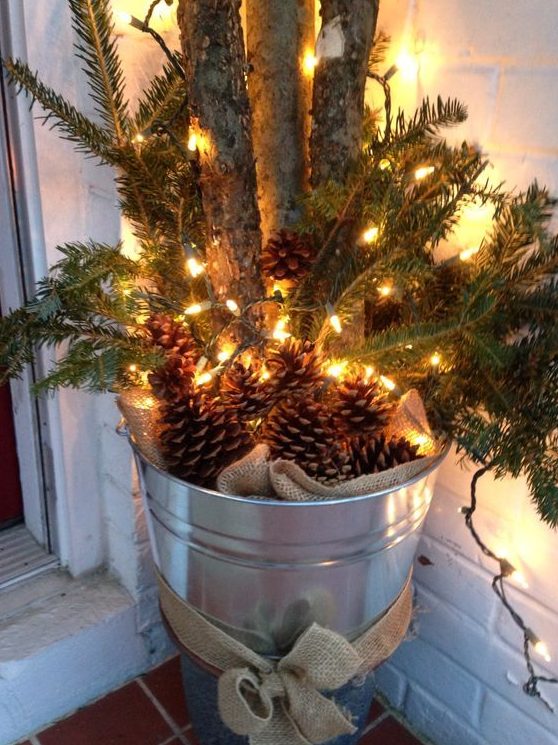 a galvanized bucket with burlap, pinecones, evergreens and branches is a cool rustic decoration for Christmas