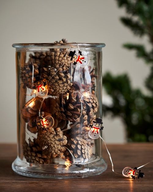 a glass jar with pinecones and snowman lights is a super cute decoration for Christmas, it looks lovely