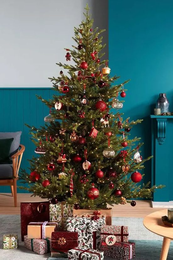 a green Christmas tree decorated with lovely red bauble ornaments and some whimsical like cupcakes and apples