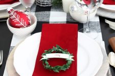 a holiday table styled with red touches, with napkins, ornaments and cranberries in glasses