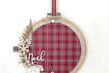 a lovely Christmas wreath made of an embroidery hoop, plaid fabric, wooden stars, snowflakes, tags and leaves is perfect for a rustic space