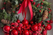 a lovely Christmas wreath of evergreens, cranberries, red ornaments and sugared apples, pinecones and a large red bow on top is a bold and cool idea