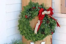 a lovely outdoor Christmas sign of wood, with large letters and an evergreen wreath with a red bow as an O letter