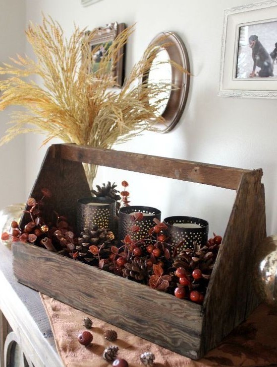 a natural fall centerpiece of a toolbox with berries, cinnamon bark, candleholders and a wheat arrangement