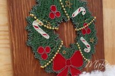 a pretty Christmassy string art showing a wreath in green, with red ornaments, candy canes and a bow is a cool and chic idea