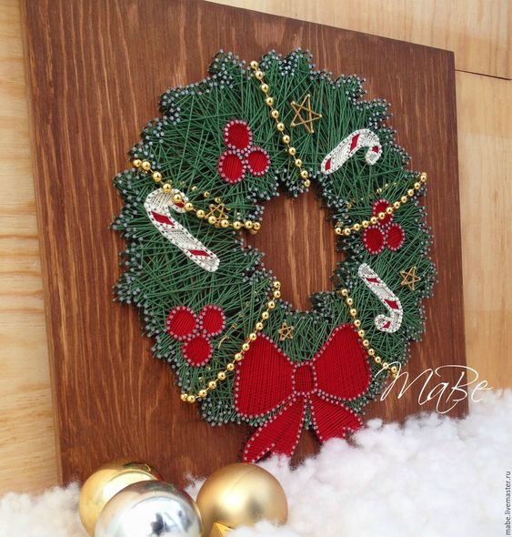 a pretty Christmassy string art showing a wreath in green, with red ornaments, candy canes and a bow is a cool and chic idea