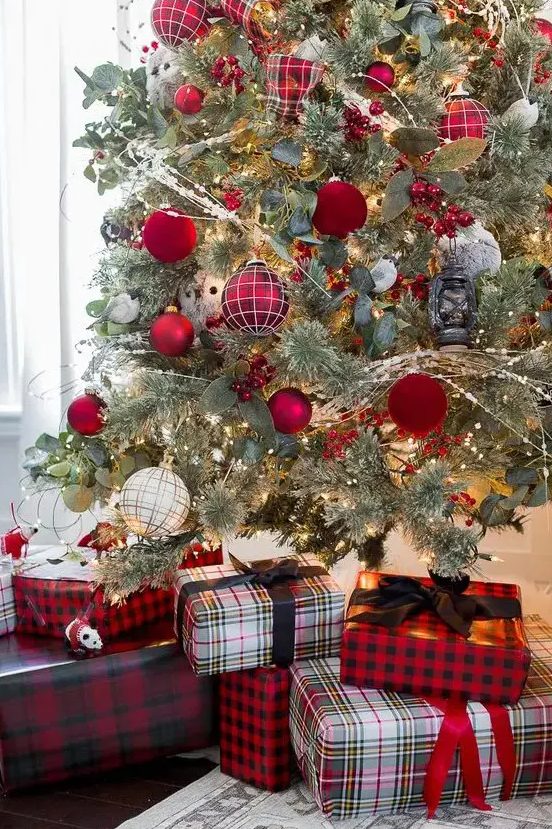 a pretty and bold Christmas tree decorated with glossy red, red velvet, red plaid ornaments and greenery plus matching gift boxes under the tree