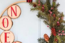 a rustic Christmas wreath with evegreens, berries and pinecones, tree slices with red letters and a plaid ribbon on top