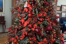 a super bold red Christmas tree with ornaments, bows, branches, ribbons and lights all covering the tree completely