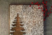 a super creative winter string art piece done with white yarn as a backdrop for the tree is wow