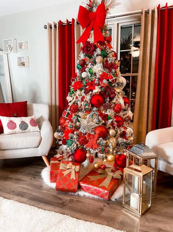 a super glam and bold Christmas tree with oversized red and gold ornaments, green stars and snowflakes and a large red bow on top