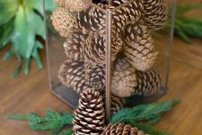 a very simple and quick Christmas centerpiece of a glass jar with pinecones, evergreens can be made in a couple of minutes