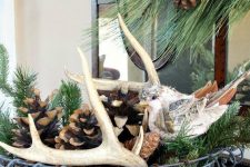 a wire basket with evergreens, antlers, birch bark and large pinecones for a modern yet rustic feel