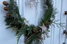 an all-natural holiday wreath covered with evergreens, branches, pinecones, branches and bark stars hanging