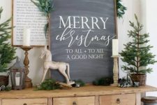 an awesome chalkboard Christmas sign decorated with greenery on top is a stylish farmhouse holiday decor idea