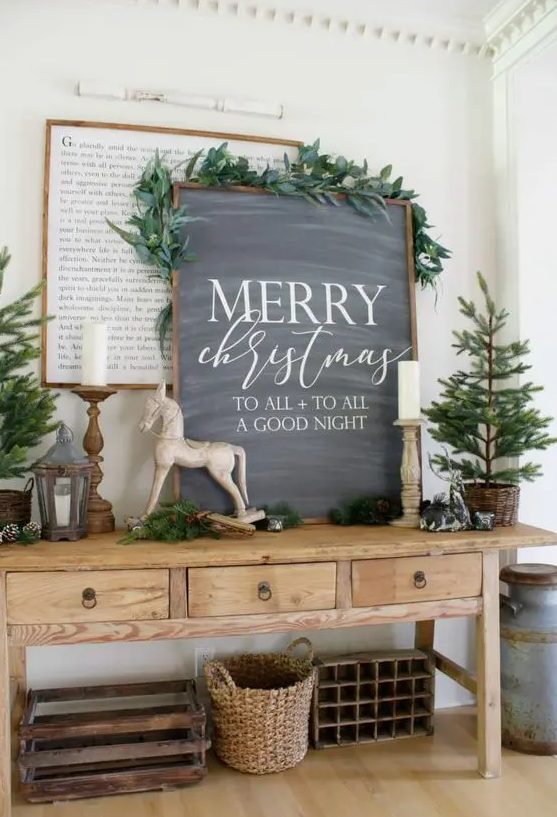 an awesome chalkboard Christmas sign decorated with greenery on top is a stylish farmhouse holiday decor idea