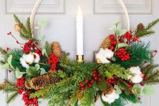 an embroidery hoop Christmas wreath with evergreens, pinecones, cotton, berries, a candle in the center is a bold idea