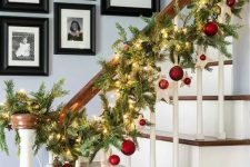 an evergreen Christmas garland with red ornaments and lights is a veyr bold and cathcy decor idea for the space