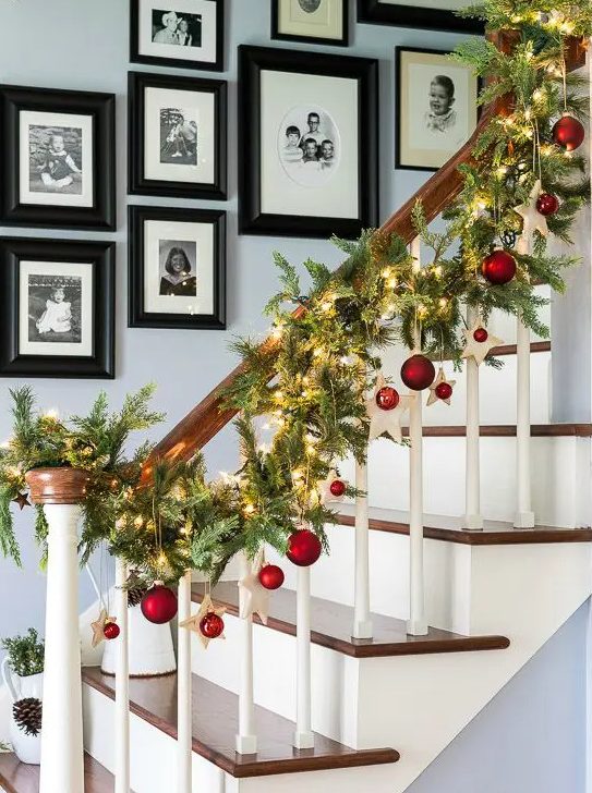 an evergreen Christmas garland with red ornaments and lights is a veyr bold and cathcy decor idea for the space