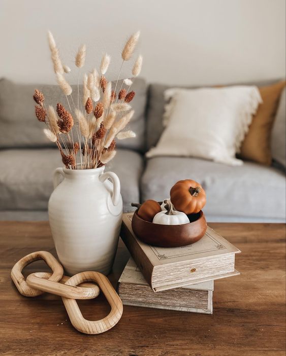 elegant Scandinavian fall decor with wooden chain, mini pumpkins and a jug with dried grasses