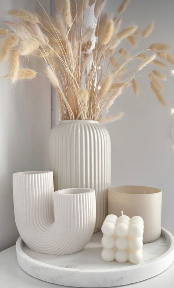 Elegant white fall Scandinavian decor with a tray, fluted vases with bunny tails, a candle in a jar and a bead shaped jar