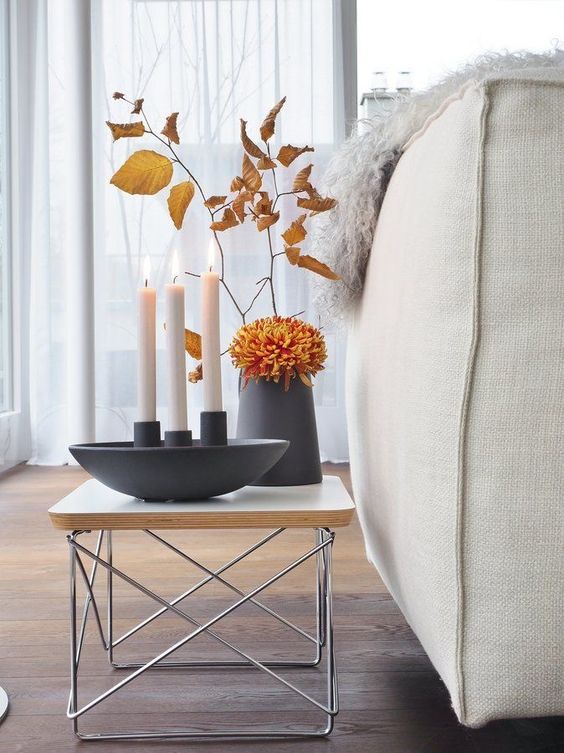 fall Scandinavian decor with a black vase with blooms and fall leaves and candles in a candleholder is a lovely idea