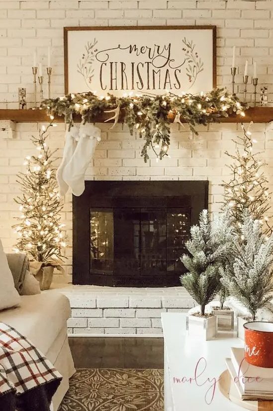farmhouse Christmas decor with evergreens, Christmas trees potted, antlers, sotckings and a sign