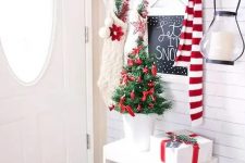 red and white ornaments in a wire bucket, red ornaments for a tiny tree and white stockings create beautiful Christmas entryway decor