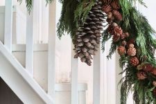 woodland banister decor for Christmas done with evergreens and small and large pinecones is a lovely idea