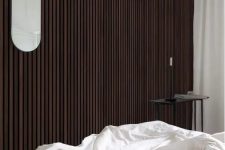 12 a catchy bedroom with a dark-stained wood slat accent wall, a bed with neutral bedding, a black coffee table and a black sconce