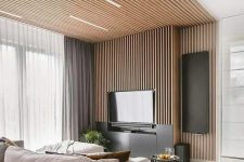 16 a contemporary living room with a wood slat wall and a ceiling, a TV , a neutral sofa and a pouf plus coffee tables