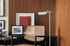 20 a mid-century modern living room with stained wood slat accent walls, a rattan chair, a black table and bright artwork
