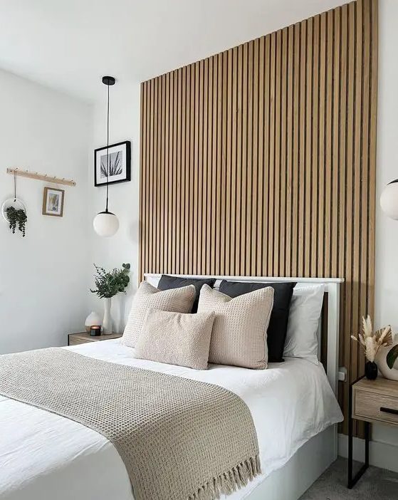 a modern bedroom with a wood slat accent wall, a bed with neutral bedding, nightstands and some lovely decor
