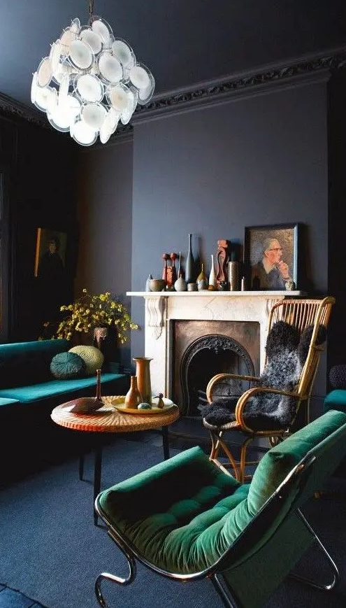 navy and black living room with emerald furniture and an antique fireplace with some decor on the mantel