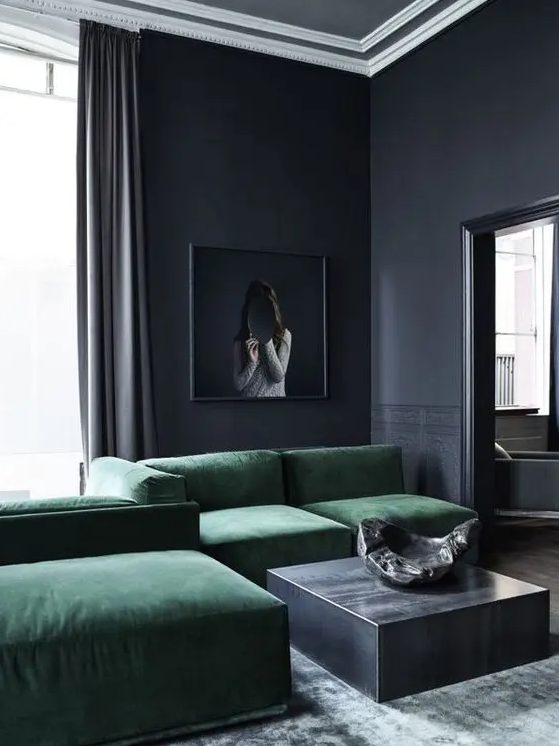 a minimalist moody living room with a green sectional, a graphite grey coffee table and some decor