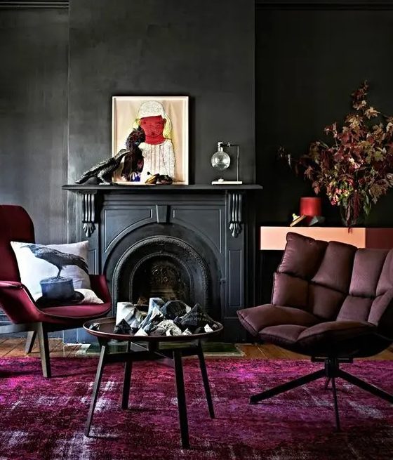 a moody living room with a an antique fireplace, burgundy seating furniture, some decor and a round coffee table