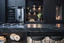 30 a black moody kitchen with plain cabinets and a stunning black marble kitchen island for a refined feel