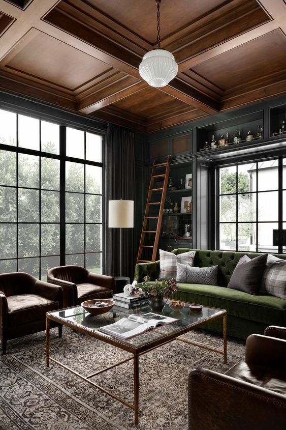 a refined graphite grey living room with a green sofa, brown leather chairs, pendant lamps and a coffee table
