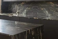 31 a minimalist black kitchen with sleek cabinets, black marble countertops and a backsplash and neutral fixtures