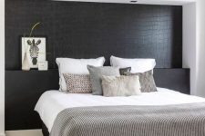 33 a Nordic bedroom with a black statement wall that imitates reptile skin and is a unique and dramatic accent