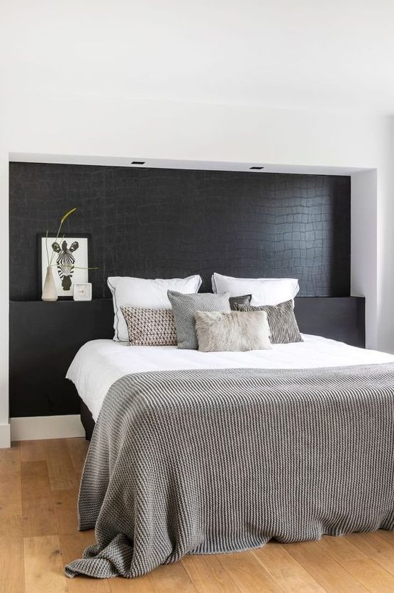 a Nordic bedroom with a black statement wall that imitates reptile skin and is a unique and dramatic accent