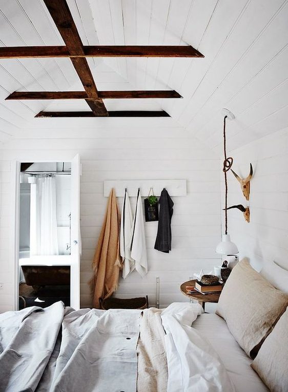 white wooden plank walls contrast dark wooden beams creatign a welcoming farmhouse bedroom