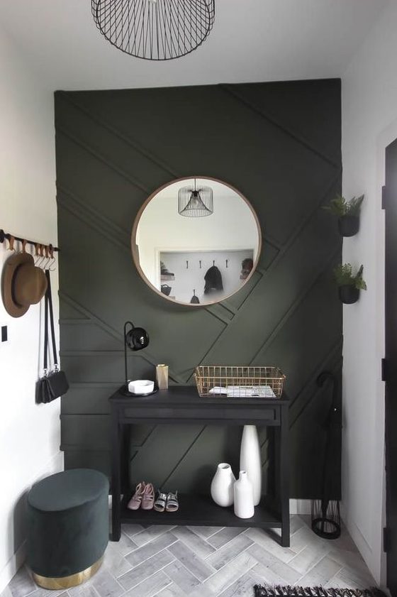 a modern entryway done in neutrals and with a black paneled wall plus some dark furniture for a very chic and cool look