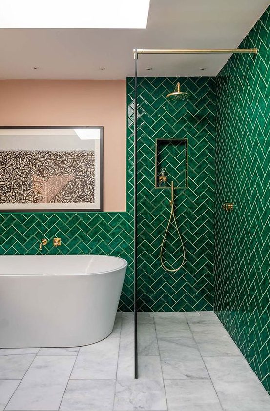 bright emerald tiles clad in a herringbone pattern, with a pink wall and touches of gold