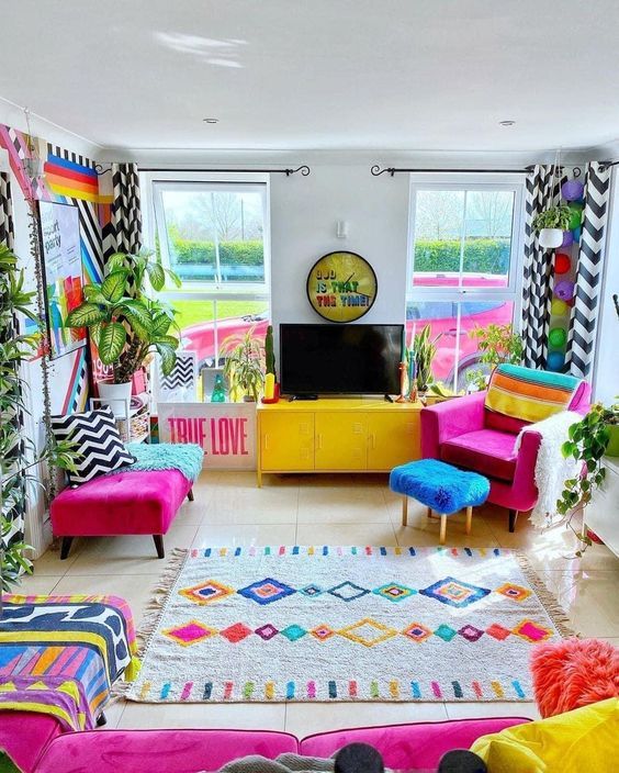 a bright and colorful living room with fuchsia seating furniture, bold printed textiles, potted plants and a mirror