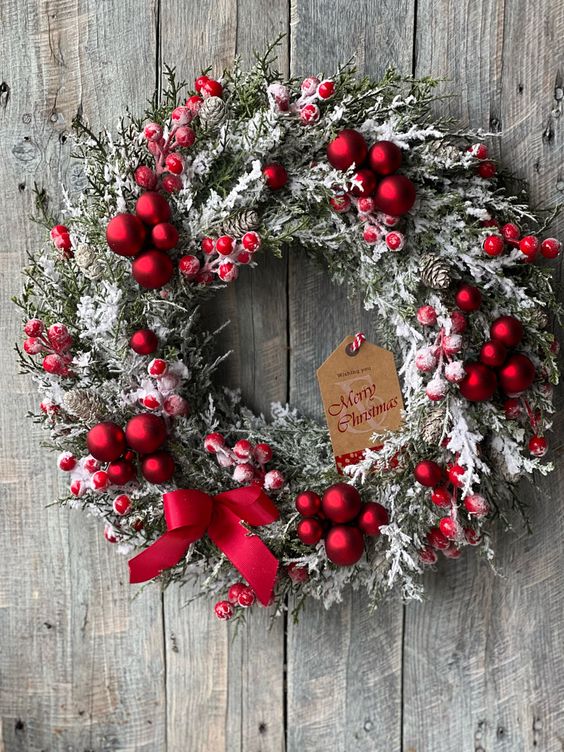 a beatiful frozen Christmas wreath with red ornaments, berries, a red bow and a tag is a gorgeous decor idea
