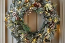 a beautiful flocked Christmas wreath with lights, twigs and pinecones is a lovely winter decoration