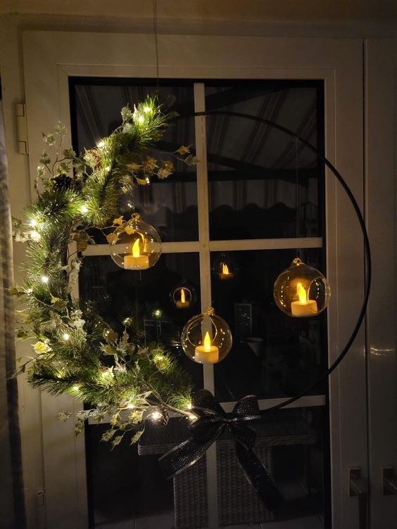 a beautiful holiday wreath with lights, evergreens, twigs and hanging candleholders is a cool Christmas decoration