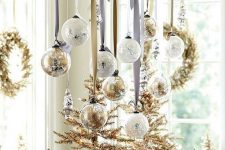 a branch with gold tinsel and white and gold ornaments is a cool Christmas ornament display